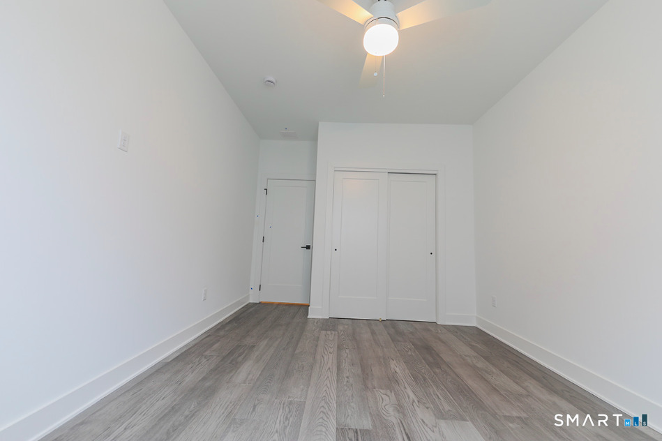 35 Lookout Ridge, Unit 35 Danbury, CT 06810 - Photo 32 of 38 an empty room with wooden floor and fan