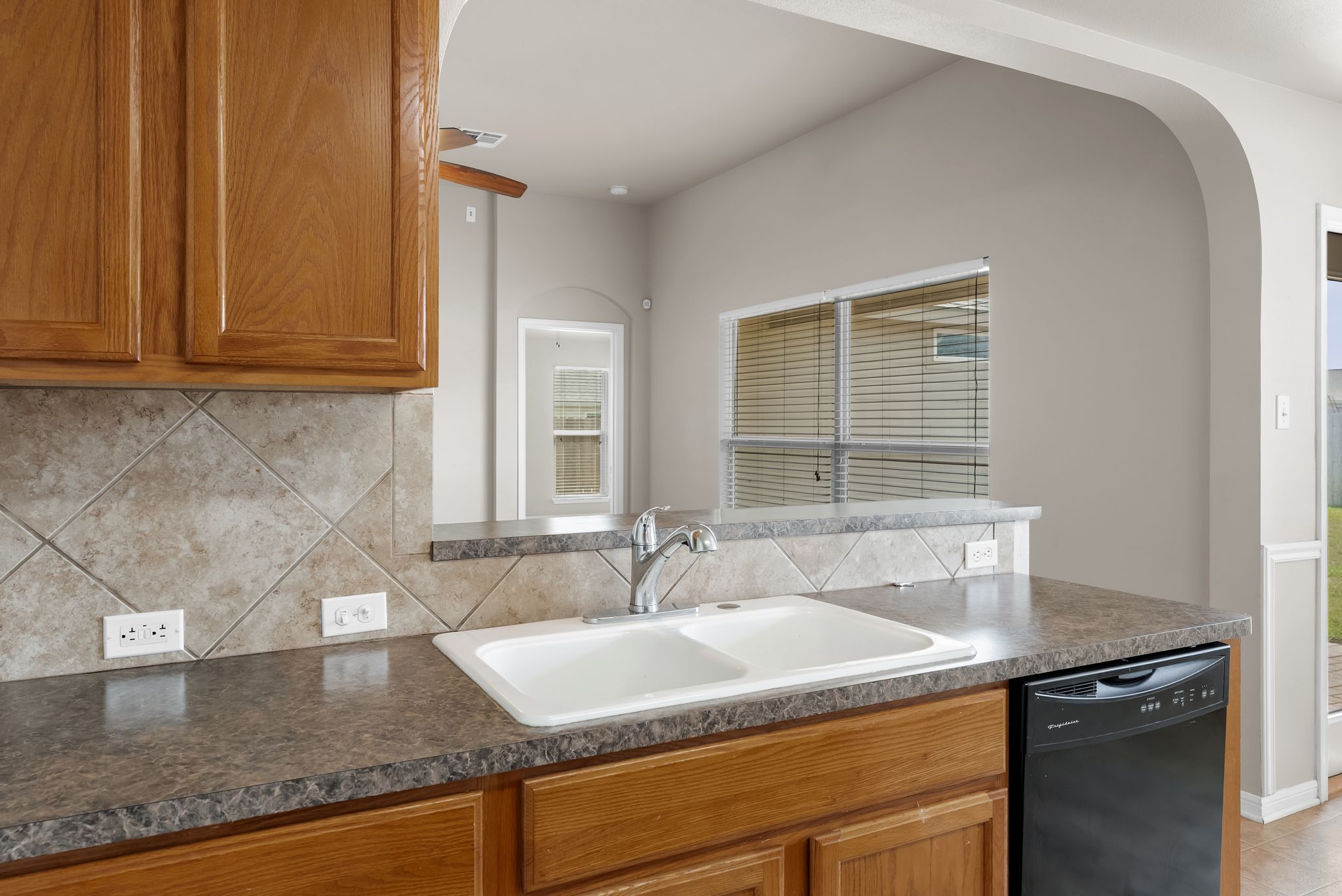 7719 Fieldstone Drive Temple, TX 76502 - Photo 21 of 37 Kitchen featuring wood finish cabinetry, dishwasher, dark countertops, and decorative backsplash