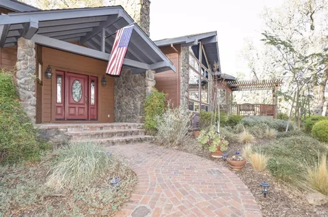 a view of a brick house with plants and large tree