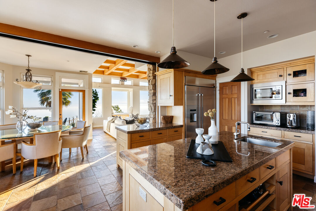 401 Moonrise Drive Malibu, CA 90265 - Photo 13 of 47 a kitchen with stainless steel appliances granite countertop a stove a sink a dining table and chairs with wooden floor