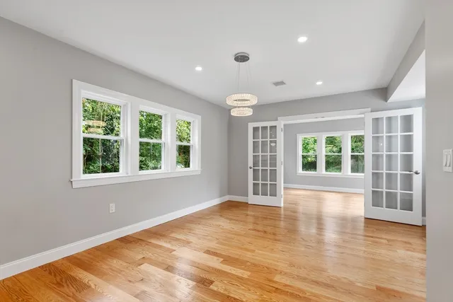 a view of an empty room with a window and wooden floor