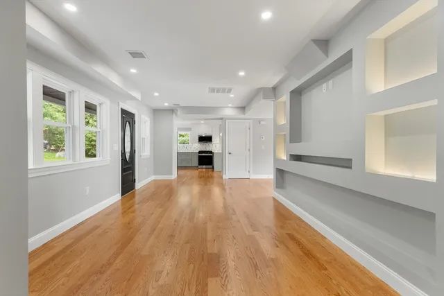a view of empty room with wooden floor and window