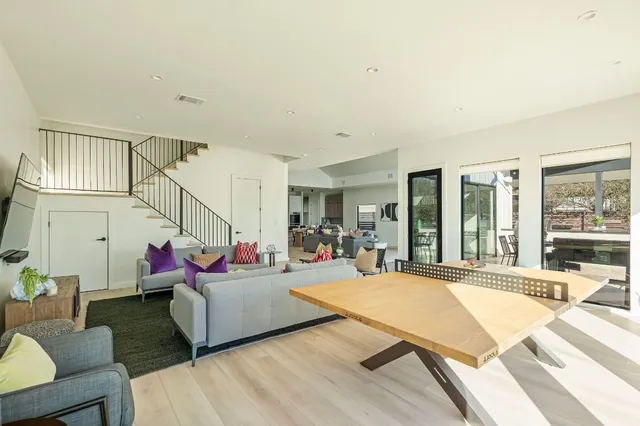 a living room with rug couches and a dining table with wooden floor