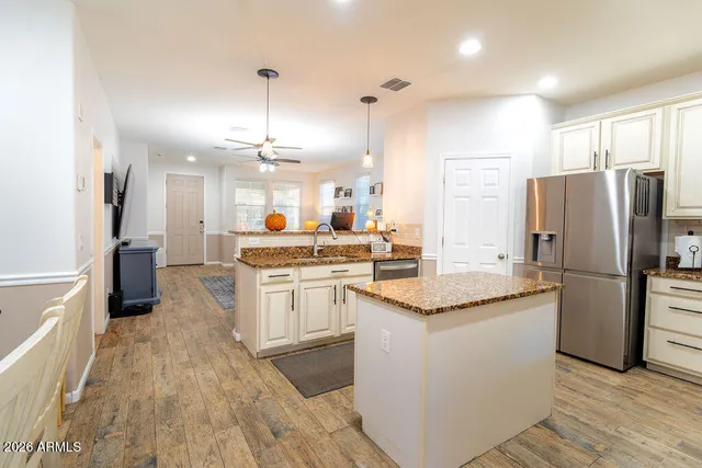 a kitchen with stainless steel appliances granite countertop a refrigerator a sink dishwasher a stove and a oven with wooden floor