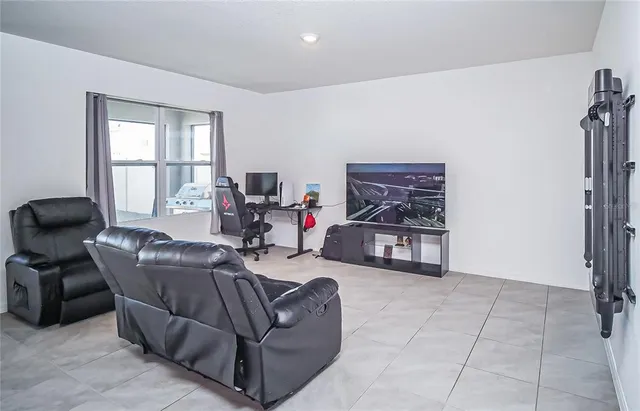 a living room with furniture a flat screen tv and a window