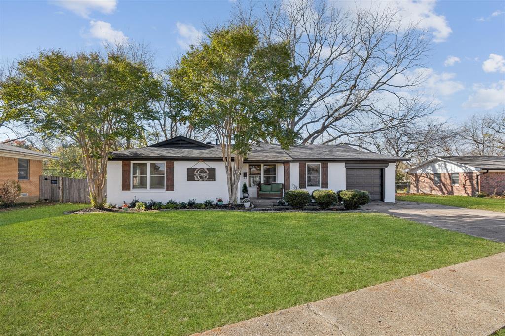 207 Joe White Street Rockwall, TX 75087 - Photo 1 of 27 a front view of a house with a garden and trees