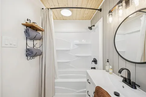 a bathroom with a sink and mirror with bathtub