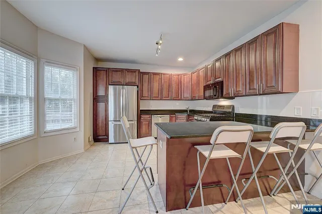 a kitchen with stainless steel appliances granite countertop a stove top oven a sink and a refrigerator