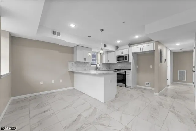 a large white kitchen with kitchen island a sink stainless steel appliances and cabinets