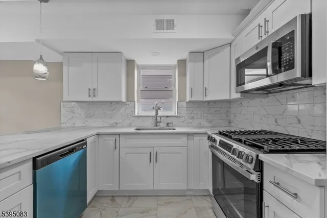 a kitchen with cabinets appliances a sink and a counter top space