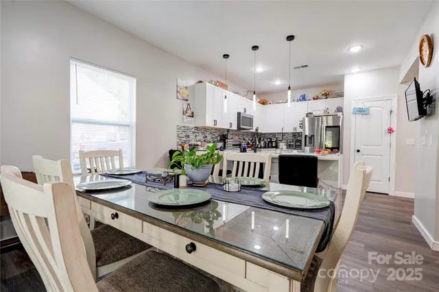a kitchen with stainless steel appliances kitchen island granite countertop a table chairs and a refrigerator