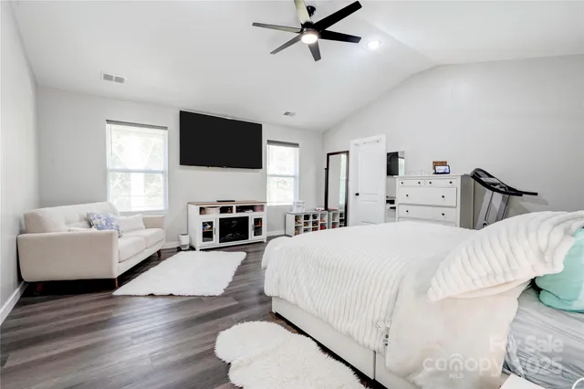 a spacious bedroom with a bed and a flat screen tv