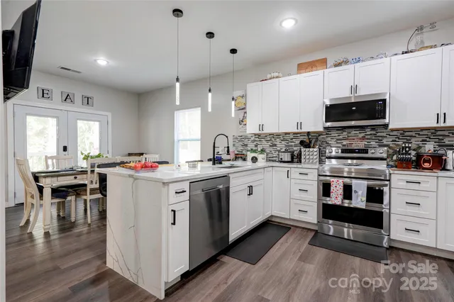 a kitchen with stainless steel appliances granite countertop a stove top oven a sink dishwasher and a refrigerator with wooden floor