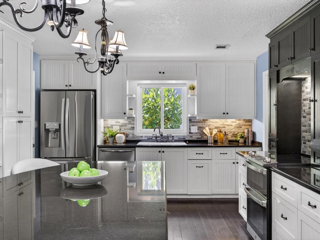 333 Cornwall Road Winter Park, FL 32792 - Photo 3 of 32 a kitchen with stainless steel appliances kitchen island granite countertop a refrigerator a stove a sink a dining table and chairs with wooden floor