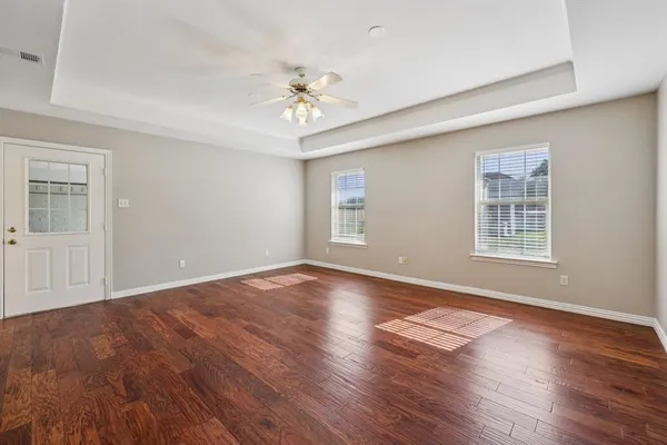 a view of an empty room with wooden floor and a window