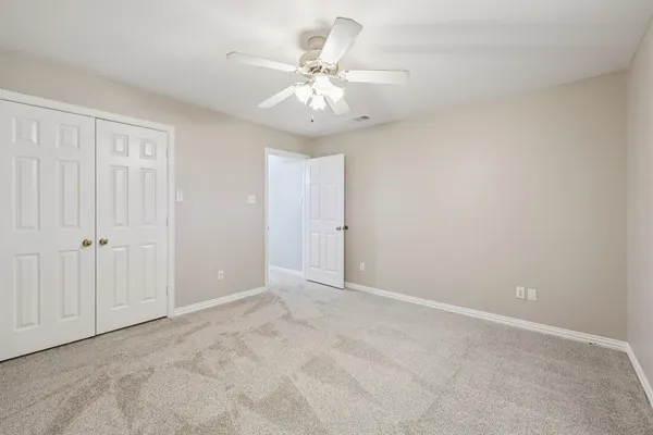 an empty room with a ceiling fan and wooden floor