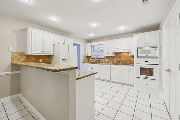 a kitchen with granite countertop white cabinets and refrigerator