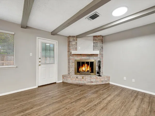 a view of an empty room with wooden floor fireplace and a window