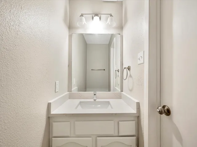 a bathroom with a granite countertop sink and a mirror