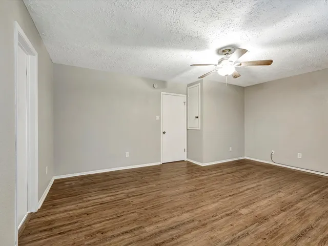 a view of a room with wooden floor and ceiling fan