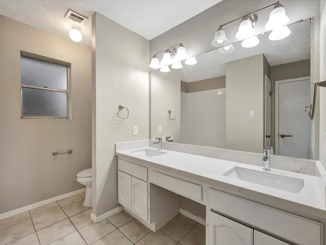 a bathroom with a double vanity sink mirror and toilet