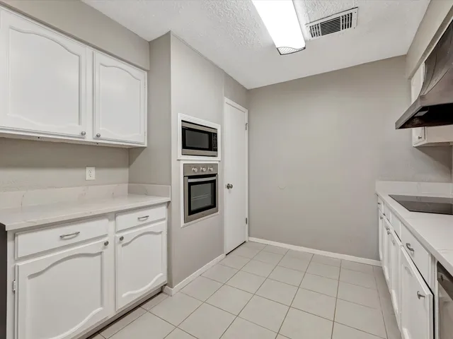 a kitchen with white cabinets and appliances
