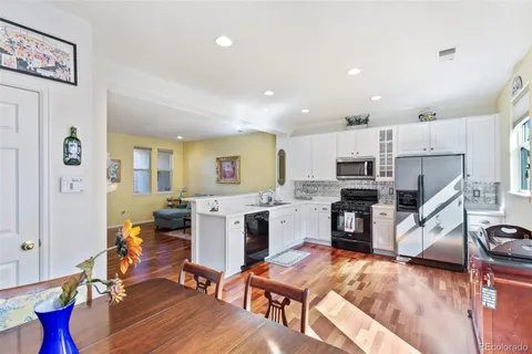 a living room with furniture and kitchen view with wooden floor