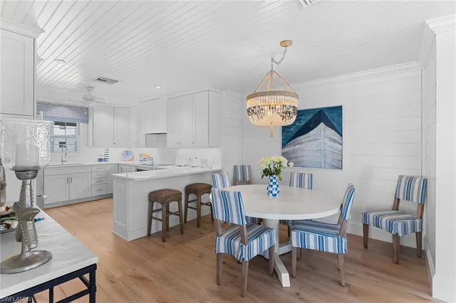 a dining room with wooden floor a chandelier a wooden table and chairs