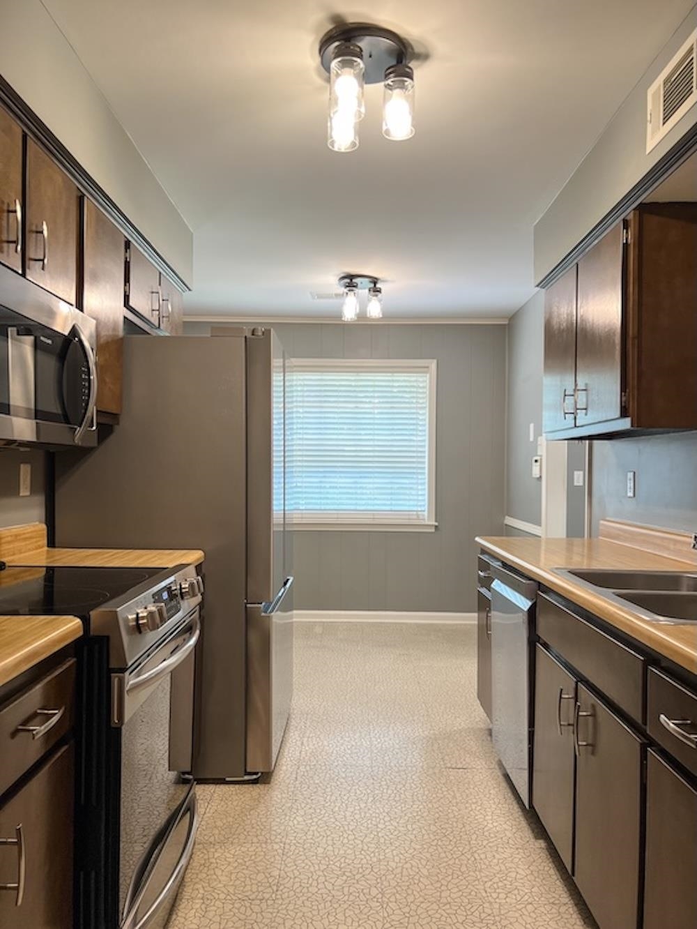 7935 Memphis Arlington Road Bartlett, TN 38133 - Photo 4 of 20 Galley kitchen featuring wood-finish cabinetry, stainless steel appliances, and a window with blinds
