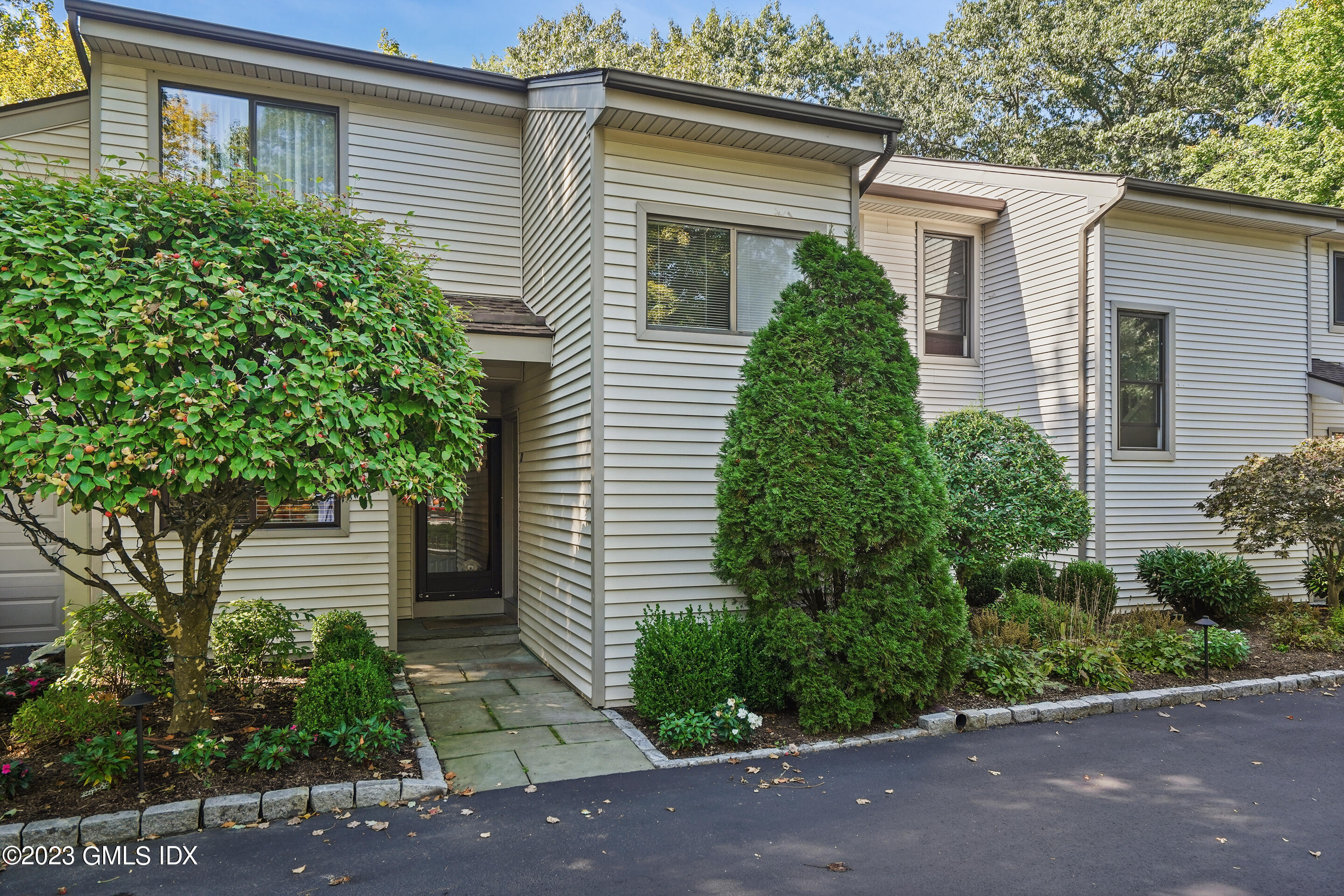 500 River Road, Unit 12 Cos Cob, CT 06807 - Photo 2 of 30 a view of a house in front of a yard with plants and large tree