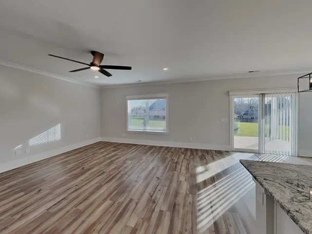 a view of a livingroom with wooden floor and a ceiling fan