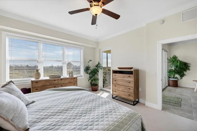 a bedroom with a bed a dresser and a large window