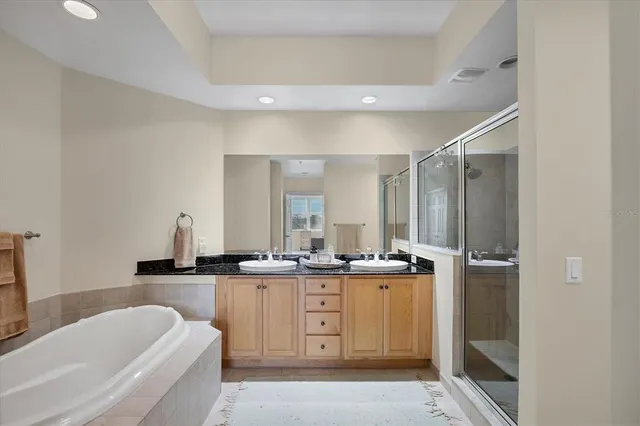 a bathroom with a granite countertop sink a bathtub a mirror and vanity