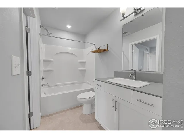 a view of an empty room with wooden floor and a ceiling fan