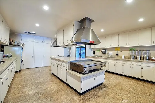 a large white kitchen with lots of counter space a sink a stove and chairs
