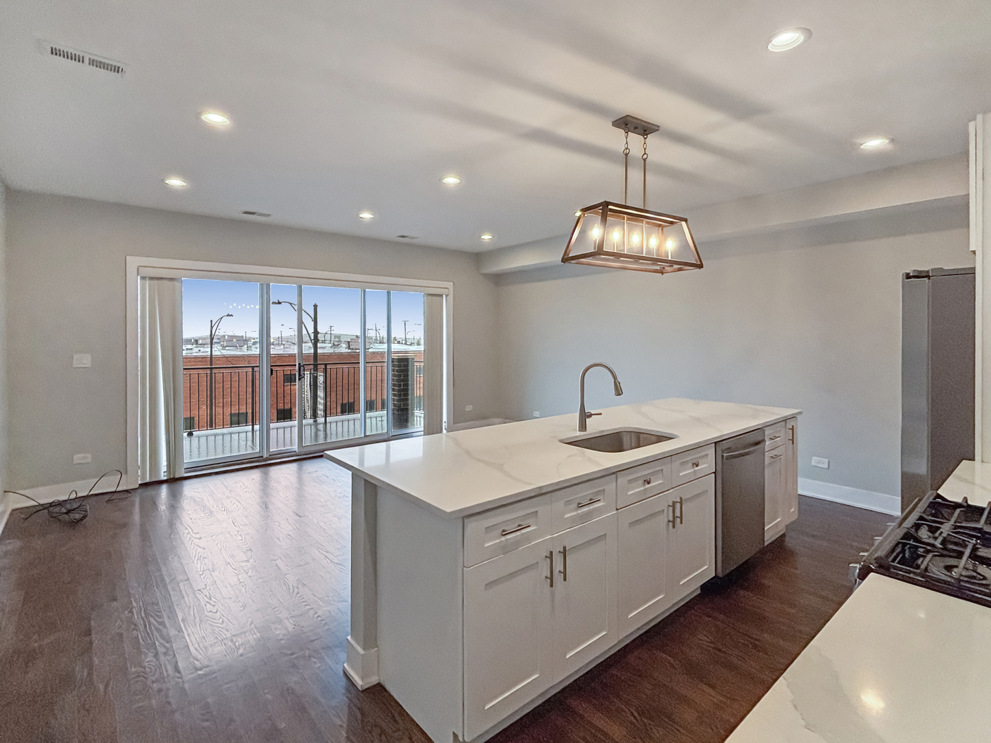 1634 West Cermak Road, Unit 3 Chicago, IL 60608 - Photo 5 of 19 a large kitchen with stainless steel appliances granite countertop a sink dishwasher a stove and white countertops with wooden floor