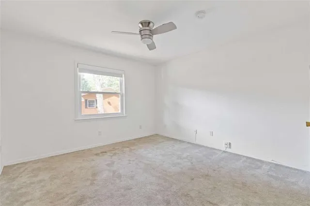 an empty room with ceiling fan and window