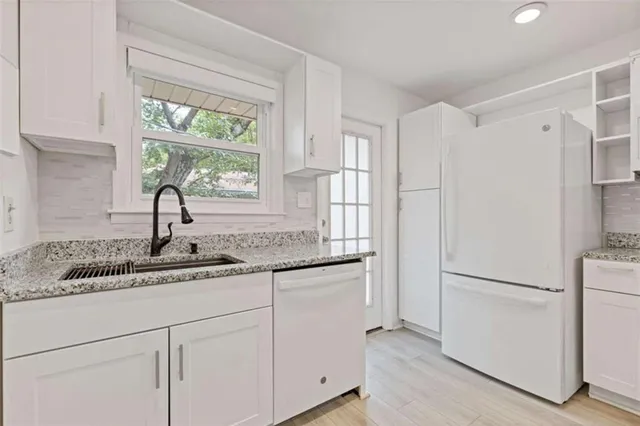 a kitchen with stainless steel appliances granite countertop a sink and a refrigerator