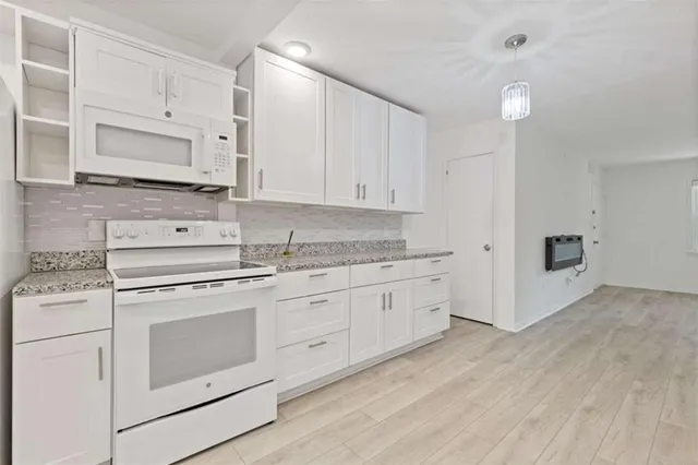 a kitchen with granite countertop white cabinets and white appliances