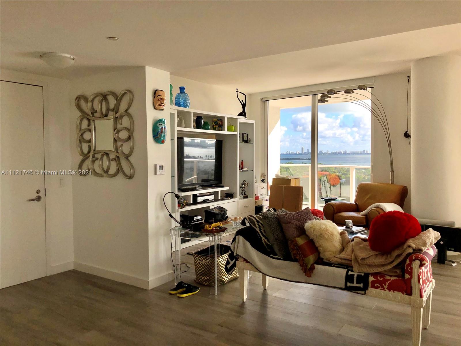 4250 Biscayne Boulevard, Unit 1601 Miami, FL 33137 - Photo 6 of 18 a living room with furniture a flat screen tv and a floor to ceiling window