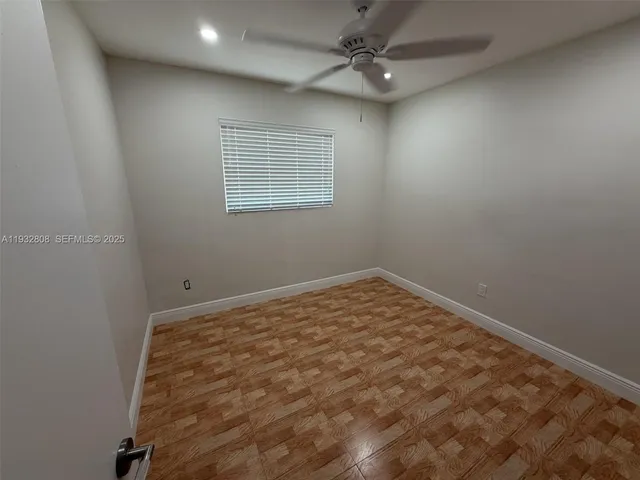 an empty room with a ceiling fan and window