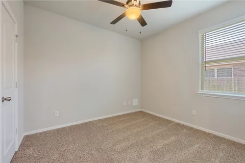 an empty room with a window and a fan