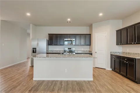 a view of a kitchen with kitchen island a sink wooden floor and counter top space