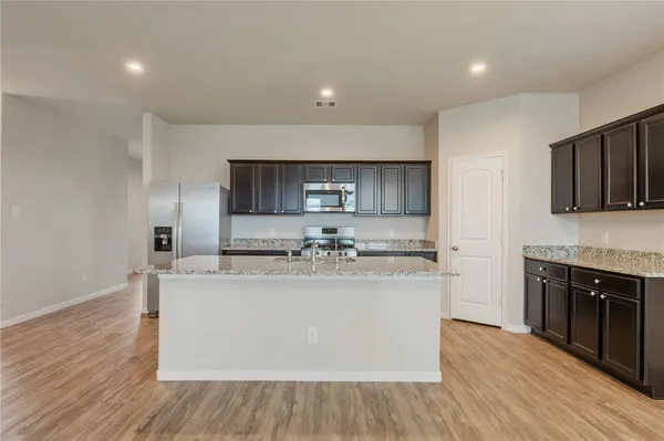 a view of a kitchen with kitchen island a sink wooden floor and counter top space