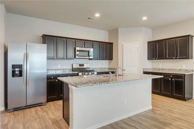 a kitchen with stainless steel appliances granite countertop a refrigerator stove microwave and sink