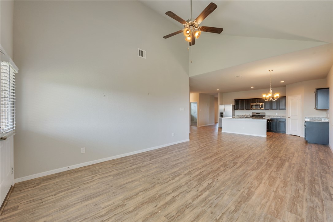 1700 Eagle View Drive Navasota, TX 77868 - Photo 5 of 22 an empty room with wooden floor a kitchen view and a ceiling fan