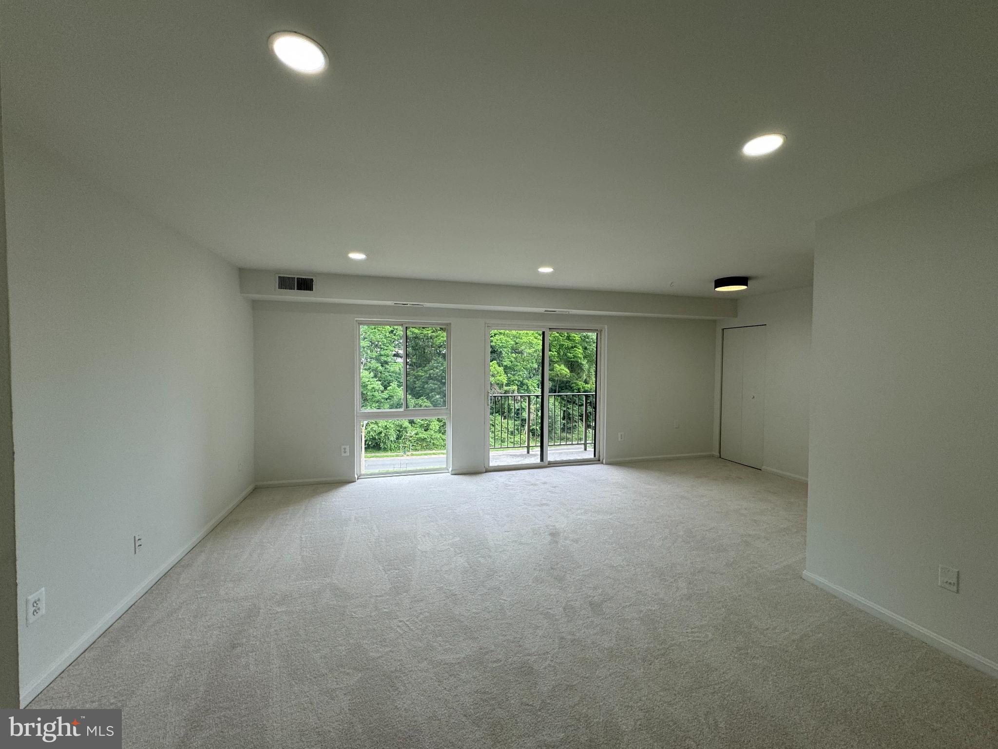 6135 Edsall Road, Unit N Alexandria, VA 22304 - Photo 2 of 9 an empty room with large windows and a fireplace
