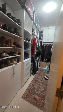 a view of walk in closet with clothes and shoes