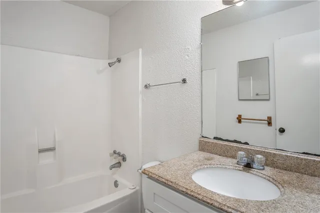 a bathroom with a granite countertop sink a mirror and a bathtub