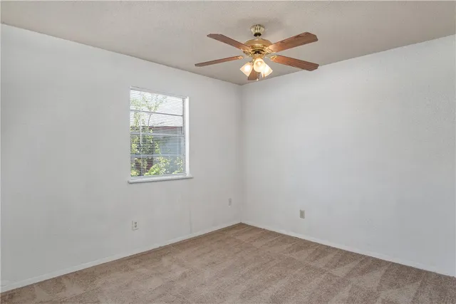 an empty room with window and chandelier fan